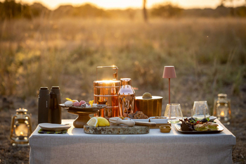 Anantara Tented Camp Kafue River: Sundowner-Snacktisch mit Fernglas im goldenen Abendlicht