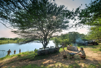 andBeyond Phinda Zuka Lodge: Busch-Dinner am Ufer im Goldlicht