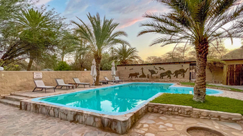 Fort Sesfontein Lodge: Poolterrasse mit Liegen im goldenen Abendlicht