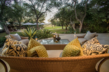 Savanna Lodge: Elegantes Rattan Sofa mit gemusterten Kissen und Laternen