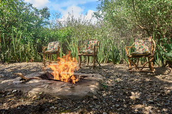 Tindiga Tented Camp: Lagerfeuer am Tag mit bunten Kissen