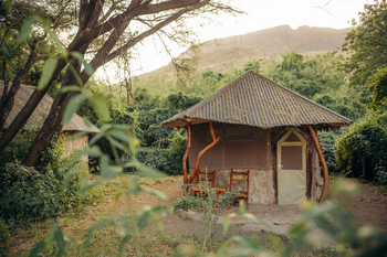 Lake Natron Tented Camp: Rustikale Hütte mit Holzstühlen im Morgenlicht