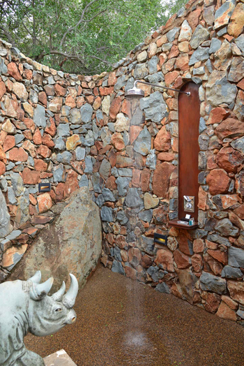 Mateya Safari Lodge: Außendusche mit Stein und Nashornskulptur