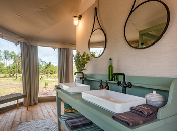 The River Camp: Offenes Badezimmer mit Doppelwaschbecken und runden Spiegeln