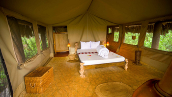 Crater Forest Tented Camp: Luxuriöses Schlafzimmer mit geschnitztem Holzbett