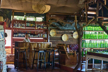 Ikoma Tented Camp: Rustikale Bar mit Spirituosensammlung und Bedienung