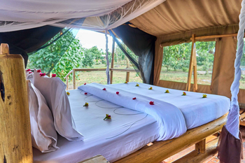 Migunga Tented Camp: Himmelbett mit Moskitonetz und Blüten