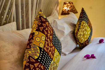 Moivaro Lodge: Bett mit bunten Kissen und Blütenblättern