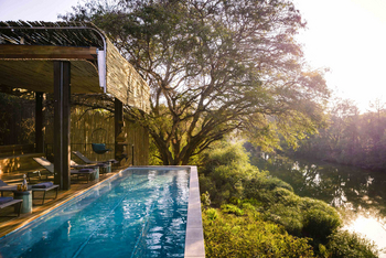 Singita Sweni Lodge: Pooldeck mit Liegen und Bambusdach am Fluss