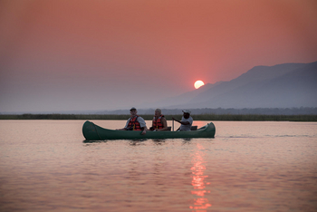 Zambezi Expeditions: Kanu im Wasser und untergehende Sonne