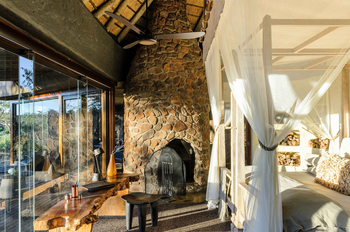 Singita Boulders Lodge: Canopy Bedroom with Stone Fireplace