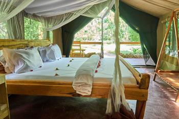 Migunga Tented Camp: Holzbetten mit Blumen und Moskitonetz