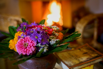 Country-Lodge: Lounge mit Blumenstrauß vor dem Kamin