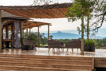The River Camp: Lounge-Deck mit Korbstühlen vor Bergkulisse
