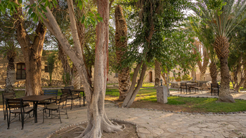 Fort Sesfontein Lodge: Holztische im schattigen Buschgarten