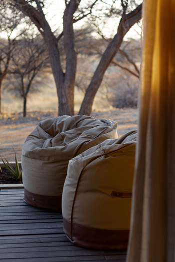 Otjiwa Thornbush Tented Camp: Holzdeck mit zwei beigen Lounge-Sitzsäcken im Nachmittagslicht