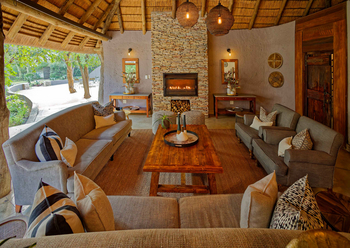 Savanna Lodge: Lounge mit Steinkamin und grauen Sofas