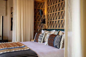 Anantara Tented Camp Kafue River: Schlafzimmer mit gewebten Kissen und Holzkopfteil