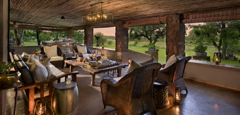 Singita Castleton: Offene Busch-Lounge mit Korbsesseln und Laternenlicht