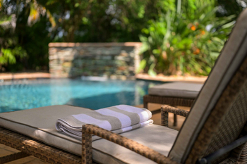 Savanna Lodge: Geflochtene Poolliege mit gestreiftem Handtuch