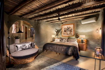 andBeyond Phinda Rock Lodge: Schlafzimmer mit Holzkopfteil und Baumstammdecke