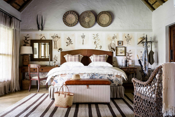 Singita Castleton: Schlafzimmer mit floralem Bett und Lederhocker