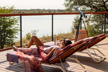 Anantara Tented Camp Kafue River: Gast entspannt am Flussdeck mit Teleskop