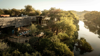 Singita Sweni Lodge: Sonnenbeschienene Holzterrasse mit Lounge und Flussblick