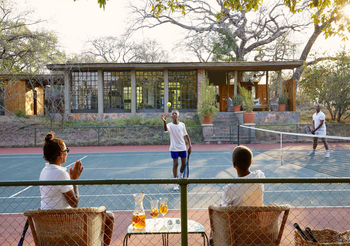 Singita Castleton: Gäste beim Tennismatch auf grünem Buschplatz