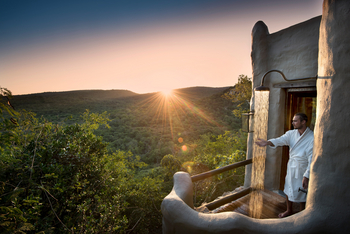 andBeyond Phinda Rock Lodge: Gast genießt Außendusche bei Sonnenaufgang.