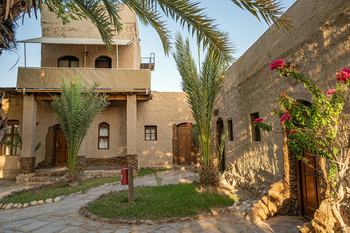Fort Sesfontein Lodge: Goldener Palmenhof mit blühender Bougainvillee