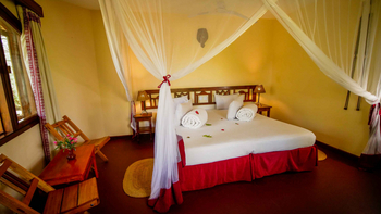 KIA Lodge: Schlafzimmer mit Moskitonetz und roten Akzenten