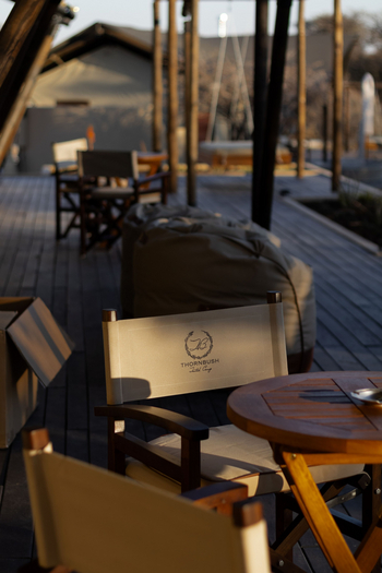 Otjiwa Thornbush Tented Camp: Lounge-Deck mit Canvas-Regiestühlen im goldenen Abendlicht