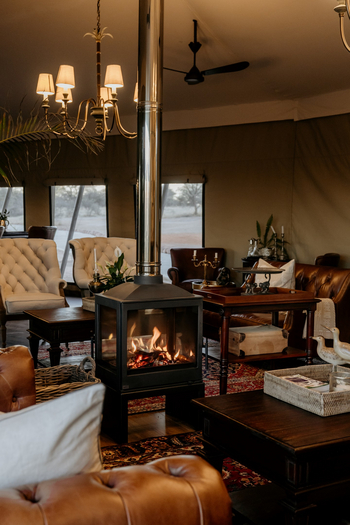 Otjiwa Thornbush Tented Camp: Lounge mit verglastem Kamin und Chesterfield-Sesseln