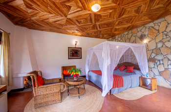 Country Lodge: Schlafzimmer mit Moskitonetz und Blumenarrangement