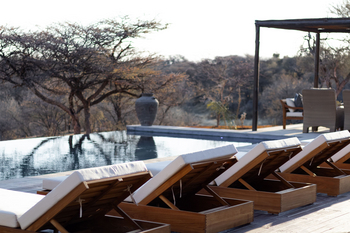 Otjiwa Thornbush Tented Camp: Infinity-Pool am Busch mit Holzliegen im Abendlicht