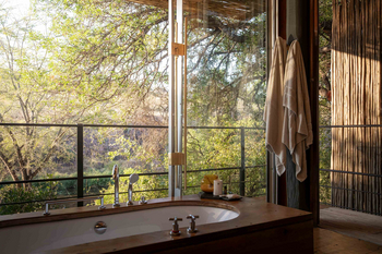 Singita Sweni Lodge: Badewanne vor Panoramafenster mit Buschpanorama