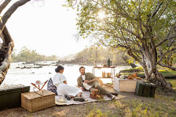Anantara Tented Camp Kafue River: Paar beim Sundowner-Picknick am Kafue-Ufer