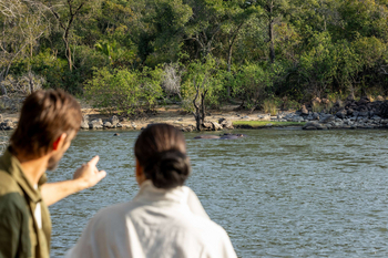 Anantara Tented Camp Kafue River: Zwei Gäste beobachten Flusspferde am Wasser