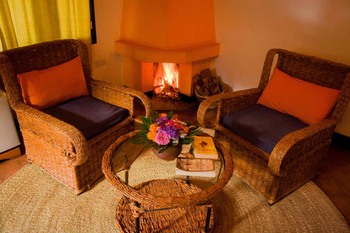 Country Lodge: Kaminlounge mit Korbmöbeln und Blumenarrangement