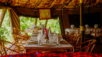 Crater Forest Tented Camp: Essbereich mit hölzernen Tischen und Federmittelpunkten