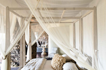 Singita Boulders Lodge: Himmelbett mit Seidenvorhang und Steinwand