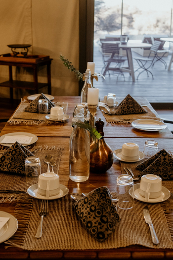 Otjiwa Thornbush Tented Camp: Essbereich mit gedecktem Holztisch und Messingvase
