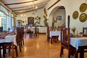 Arusha Safari Lodge: Hölzerne Esstische mit Blütenarrangements