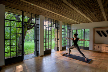 Singita Castleton: Yoga-Gast in Krieger-II-Pose vor Panoramafenstern