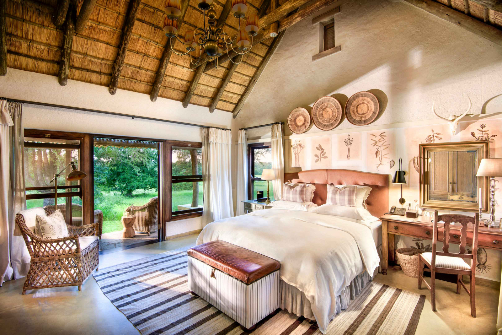 Singita Castleton Singita Castleton: Safari-Schlafzimmer mit karierten Kissen und Flechtstuhl