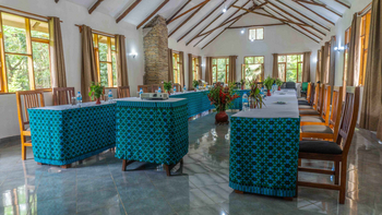 Moivaro Lodge: U-förmige Tafel mit Steinofen und Grünpflanzen