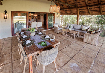 Savanna Lodge: Luftige Buschveranda mit Holztisch und Korbsesseln