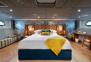 andBeyond Galapagos Explorer: Elegante Schiffskabine mit Rattan-Kopfteil und Bullaugen