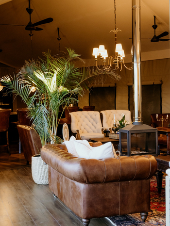Otjiwa Thornbush Tented Camp: Lounge mit Chesterfield-Ledersofa und freistehendem Kamin